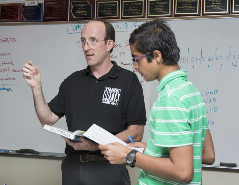 Houtrouw discusses problem-solving approaches with his AP Computer Science class, while junior Siddhant Pagariya checks his work. Houtrouw uses competition to turn hard work into fun.